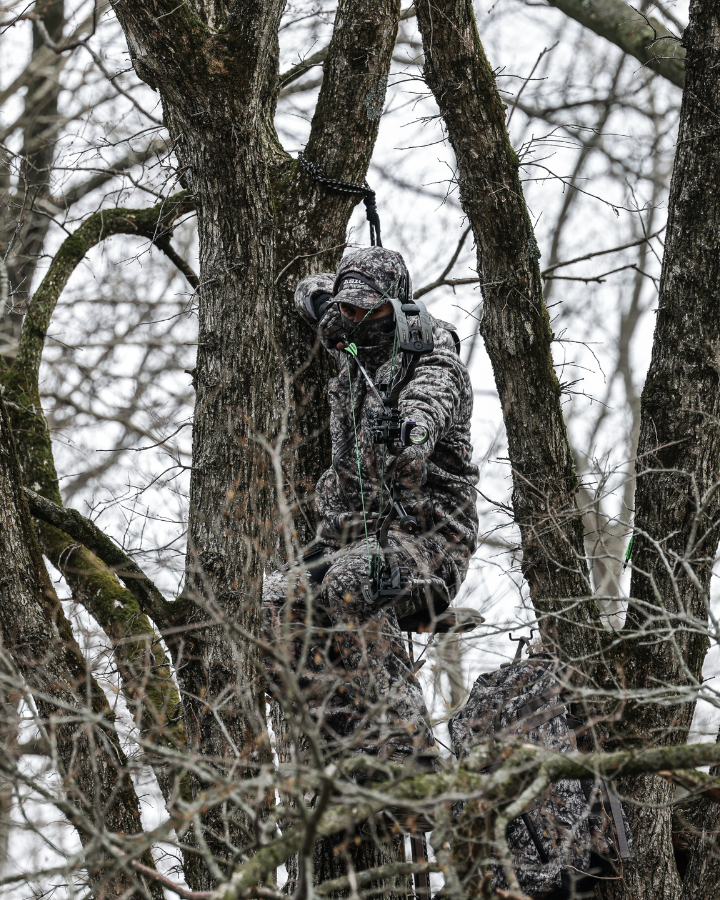 hunter wearing asio raptor camo at full draw on a whitetail during late season bow hunt