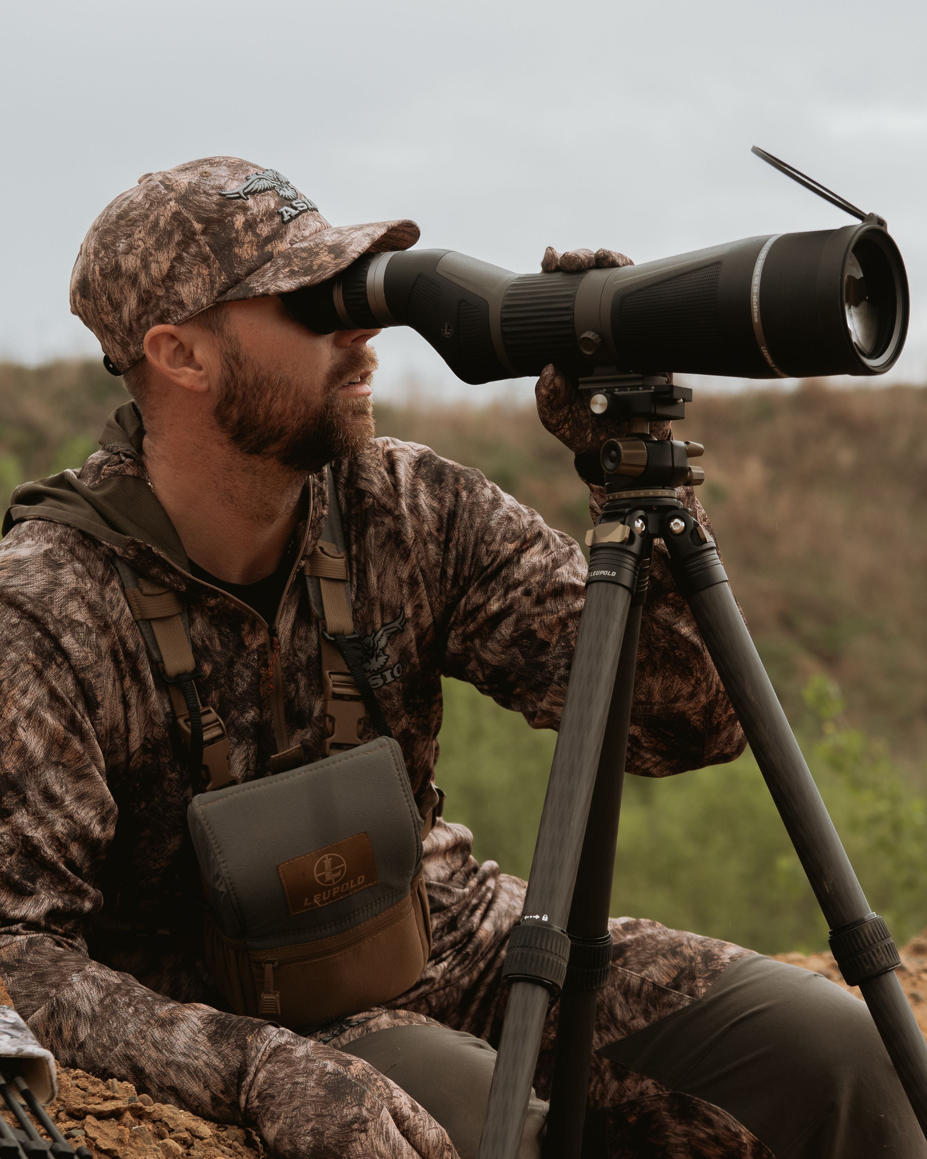 hunter wearing asio rapx camo using spotting scope to locate whitetails on western plains
