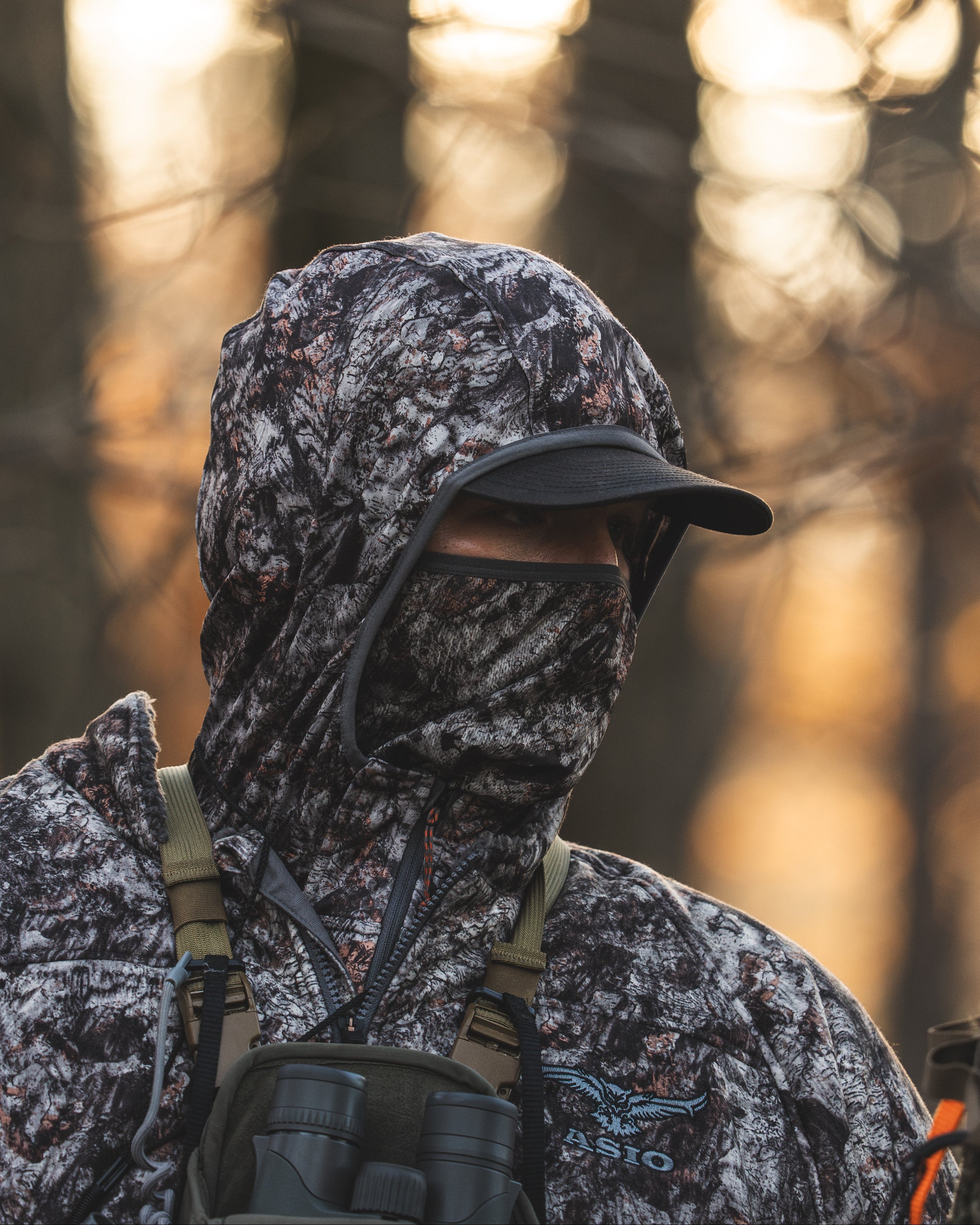 Close-up of a bowhunter wearing the ASIO Gear midweight hoodie with built-in facemask in camo, showing the hood and mask coverage for treestand hunting.