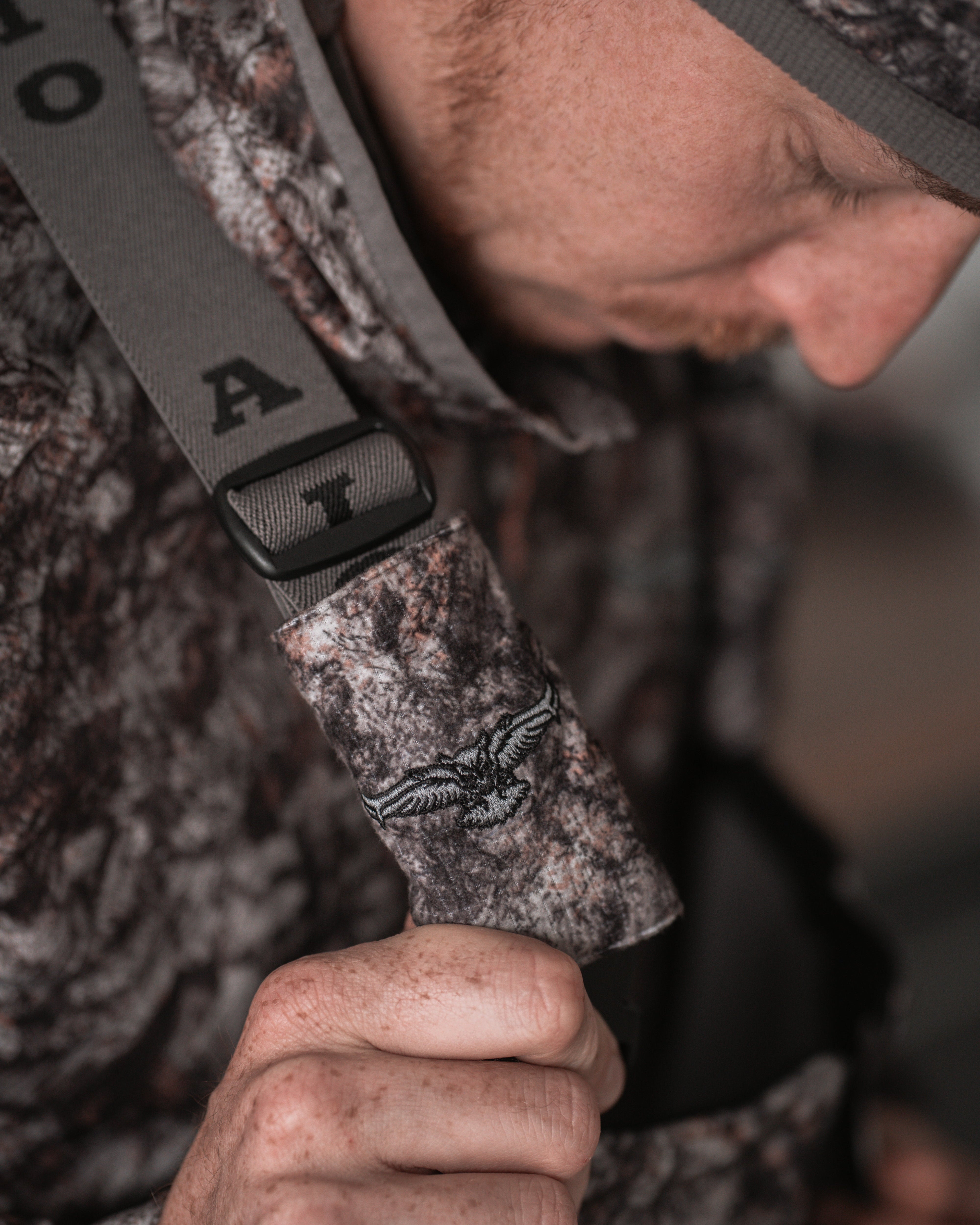 Detail of ASIO Gear logo on RAPTOR camo bib strap with bold branded suspender