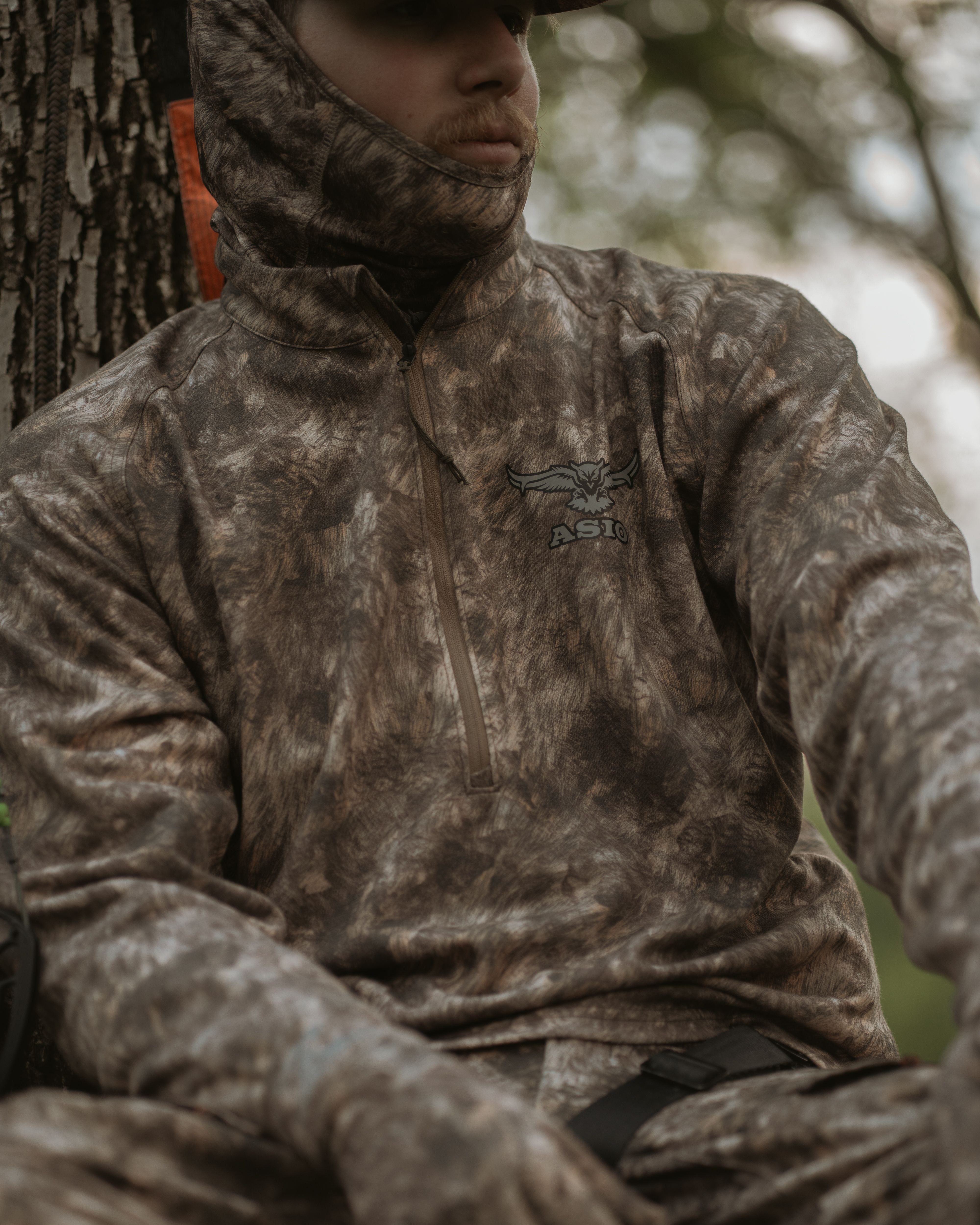 Hunter wearing ASIO Gear midweight baselayer top in RAPX camo while bowhunting from a treestand—lightweight, breathable, and stealth-ready