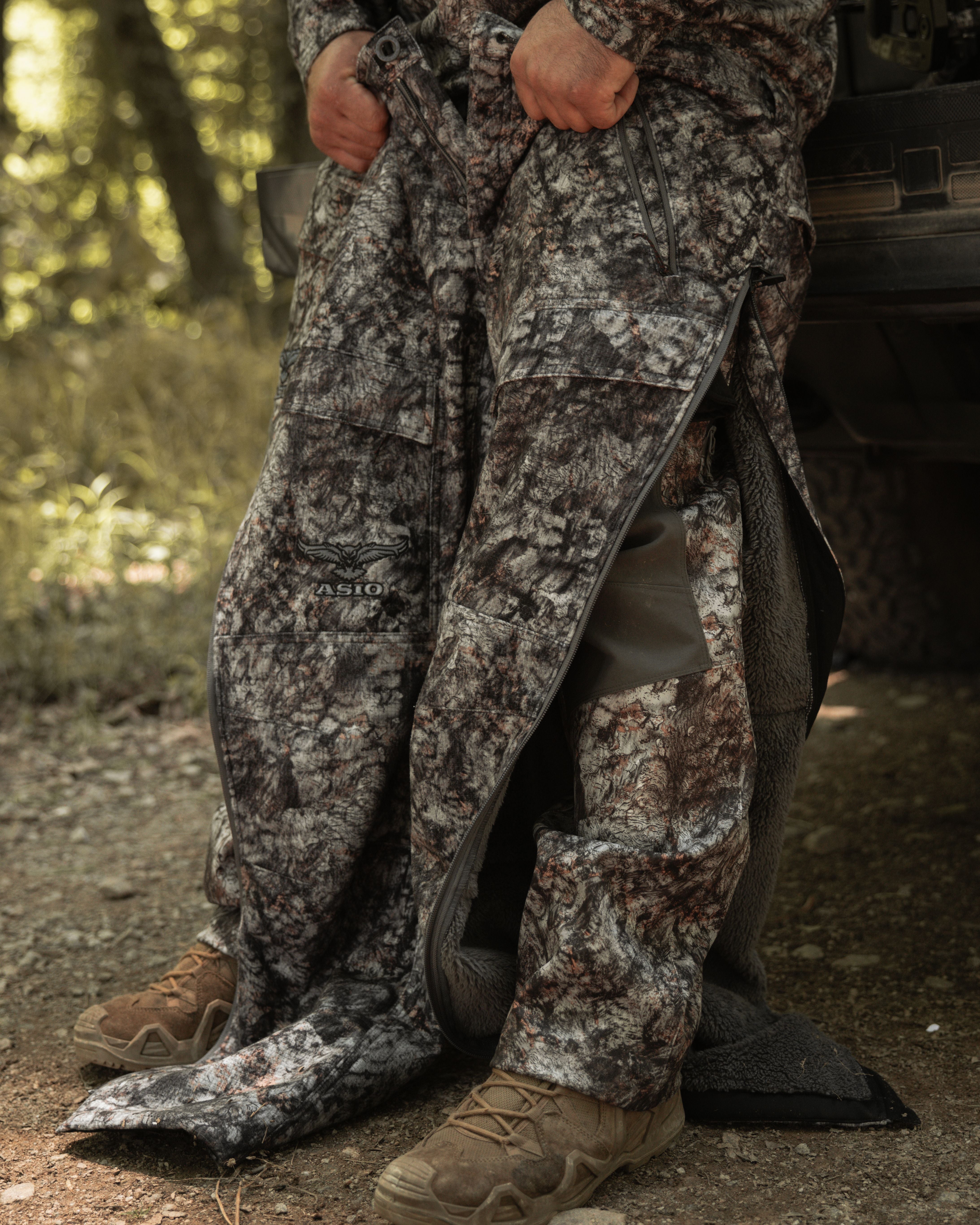 Bowhunter demonstrating full leg zip access on ASIO Gear Midweight Sherpa Pant in Raptor camo.