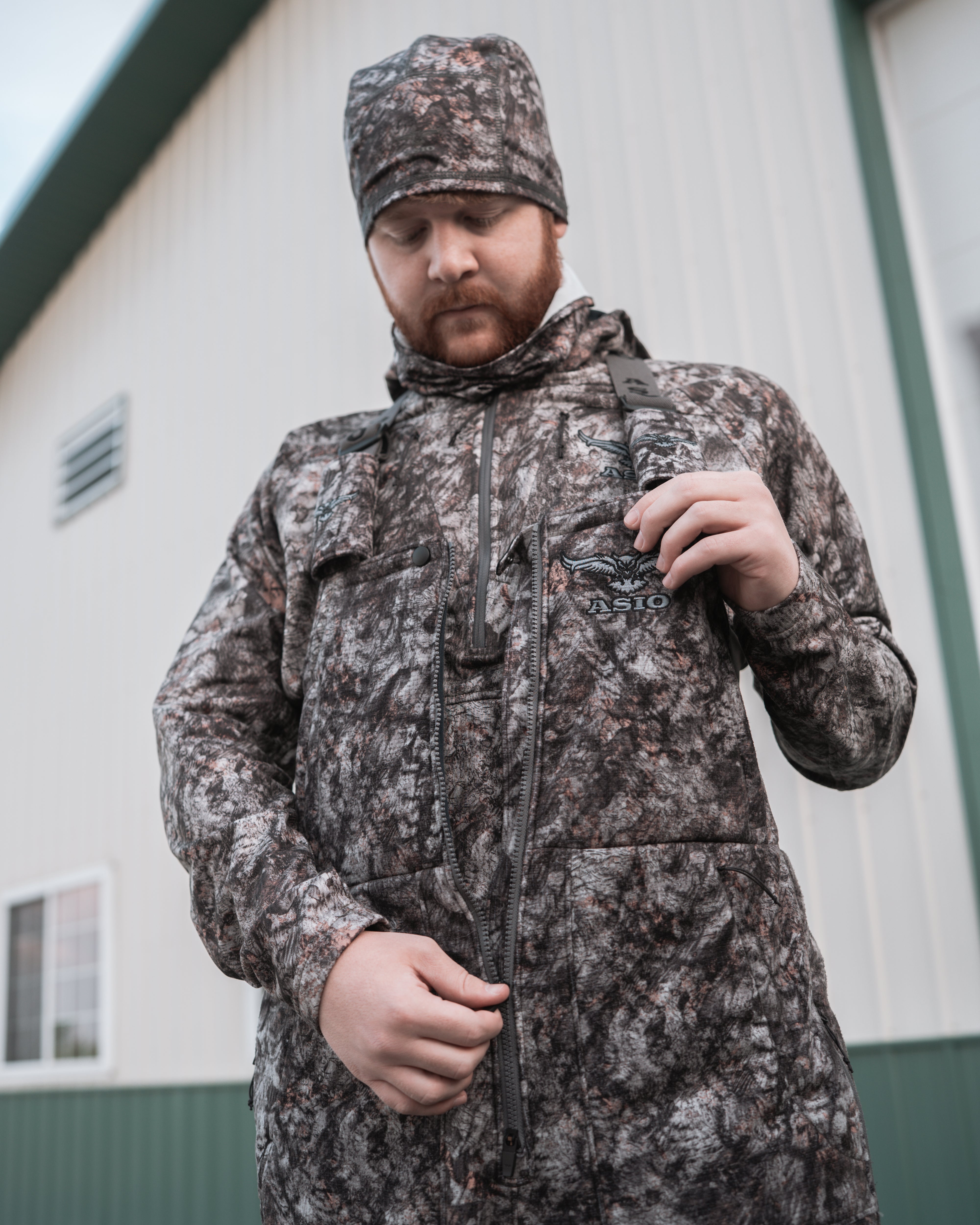 hunter zipping up raptor camo bowhunting bibs before bowhunting
