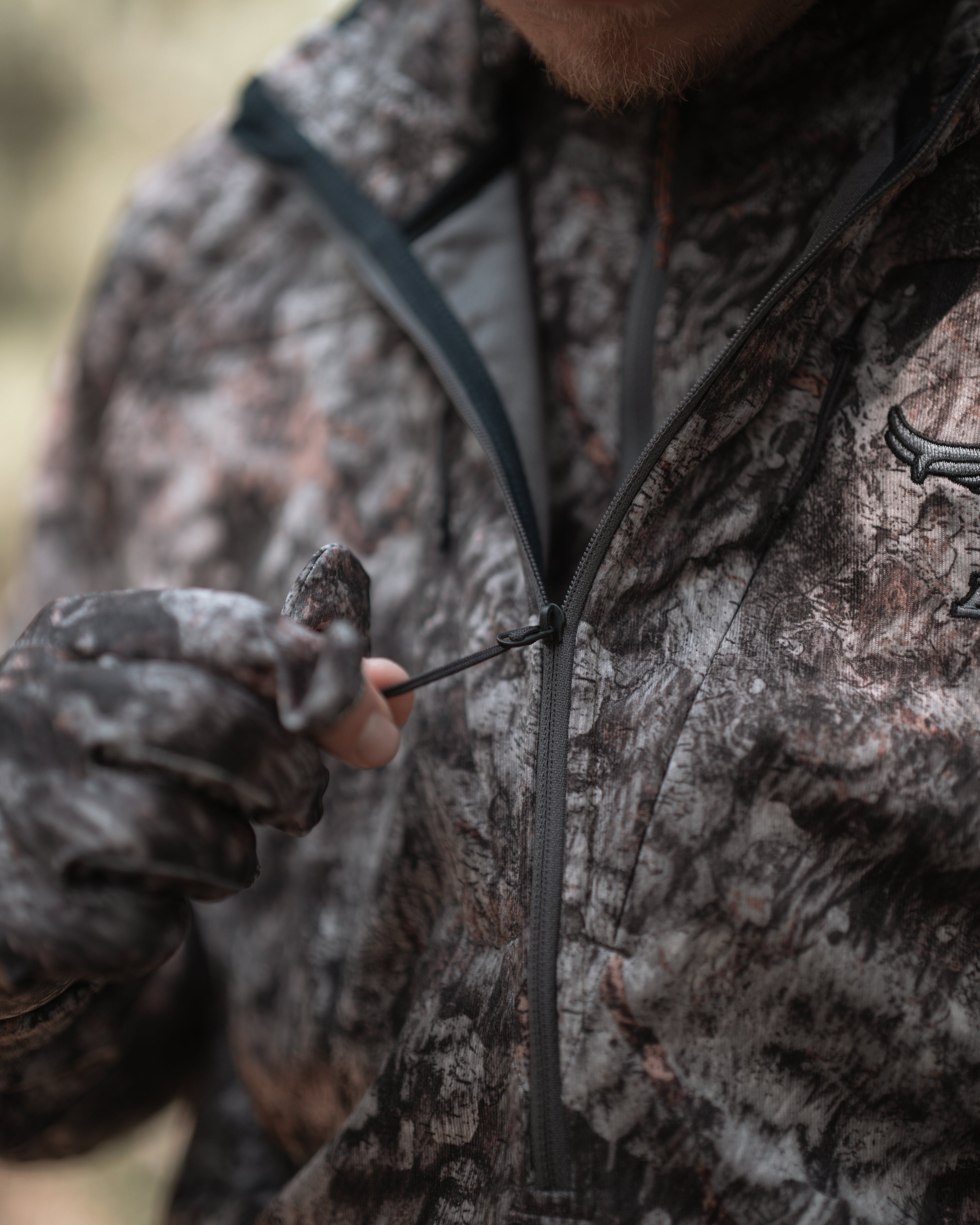 Close-up of bowhunter cinching hoodie drawcord – ASIO Midweight Hoodie in Raptor Camo.