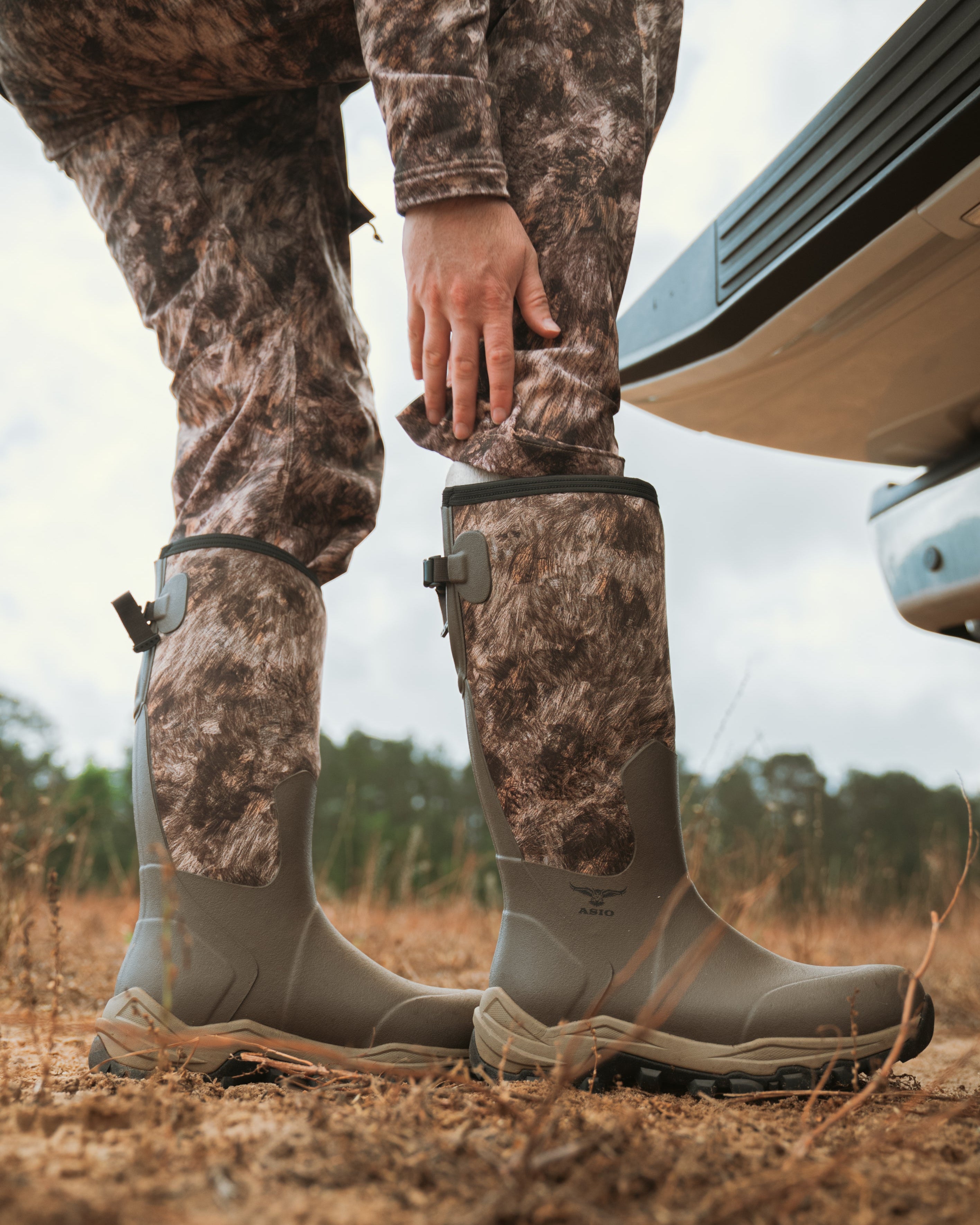 ASIO Whitetail Pro Boot in RAPX camo being adjusted before a hunt—rugged fit and elevated comfort for whitetail terrain