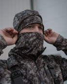 Hunter wearing ASIO Gear RAPTOR camo fleece-lined stretch beanie and face covering preparing for cold-weather bowhunt
