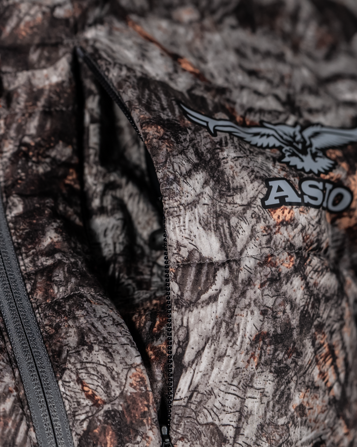 Close-up of the camo Midweight Puffy Jacket chest and Napoleon pocket zipper